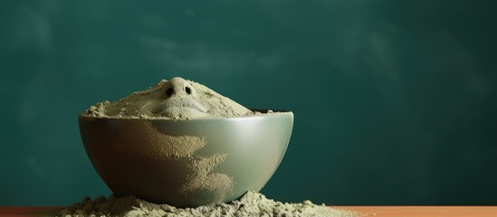 Aufkleber - A bowl contains a cosmetic clay face mask It is placed on a green background alongside some dry powder leaving space for additional content