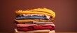 © vxnaghiyev - A close up front view of a stack of vibrant clothes on a brown background with a copy space image