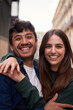 Vertical. Portrait of young multiracial couple embracing happy smiling face. Friends cheerful hugging people positive expression looking at camera. Nice loving partner posing for photo outdoors