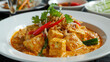 Malaysian curry tofu dish with fresh coriander, red chili, and aromatic herbs on the side