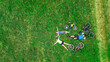 Family cycling on bikes aerial drone view from above, happy active parents with child have fun and relax on grass with bicycles, family sport and fitness outdoors
