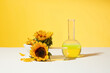 Empty stone podium with sunflowers on the sides placed on white table next to a boiling flask filled by sunflower extract over yellow background. Blank space for displaying product or adding text