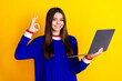 Photo portrait of pretty teen girl hold netbook okey wear trendy knitwear blue outfit isolated on yellow color background