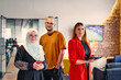 © .shock - A group of young business colleagues, including a woman in a hijab, stands united in the modern corridor of a spacious startup coworking center, representing diversity and collaborative spirit.