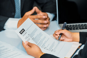 Human resources department manager reads CV resume document of an employee candidate at interview room. Job application, recruit and labor hiring concept. uds