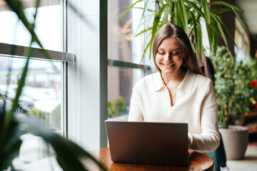 Poster - woman sitting at table using laptop computer