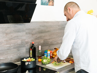 Man preparing food. 
Back view of man cooking at home kitchen