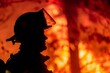 A stark silhouette of a firefighter, helmet profiled, against a blazing fire background illustrating danger and bravery in emergency situations.