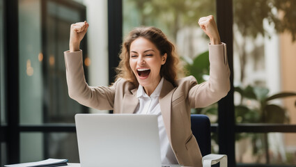 Happy overjoyed laughing businesswoman celebrating success while working on laptop in the office