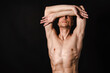 © vladorlov - A man with a beautiful body poses in the studio against a black background.