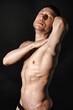 © vladorlov - A man with a beautiful body poses in the studio against a black background.
