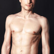 © vladorlov - A man with a beautiful body poses in the studio against a black background.