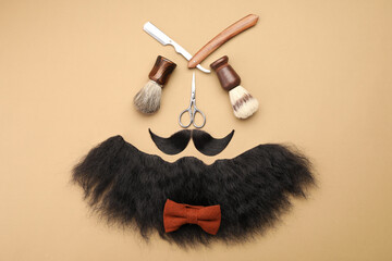 Wall Mural - Artificial moustache, beard and barber tools on beige background, flat lay