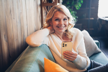 Sticker - Photo portrait of lovely retired woman sit sofa hold gadget dressed casual outfit cozy home interior living room in brown warm color