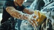 A man washes a car with a sponge.