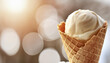 Delicious vanilla ice-cream in waffle cone on light blurred background. Sweet food. Tasty treat.