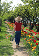 girl walking with straw hat and bucket full of blooming tulips