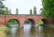 Ancient bridge with three arches over the small river made with bricks