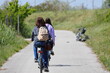 girl and her mother with backpacks on their shoulders riding their bicycles leisurely on a country bike path