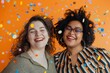 two smiling diverse women in casual clothes studio shot with a bit of confetti