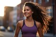 A young woman with curly hair is smiling while jogging in the city