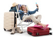 Tourist woman in travel attire, on deck chair with trolley suitcases, make selfie with mobile phone and thumbs-up. Summer beach holiday, flight and vacation travel booking. Travel influencer lifestyle