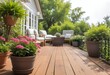 A wooden deck with potted plants and flowers, overlooking a lush green garden with trees and shrubs in the background