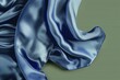 A luxurious, sapphire blue silk scarf, draped elegantly with soft folds and a slight flutter, as if caught in a gentle breeze, against a solid green background. 