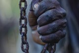 Fototapeta Kosmos - Hand of a black person holding a black chain, concept of Juneteenth, Freedom Day, end of slavery.
