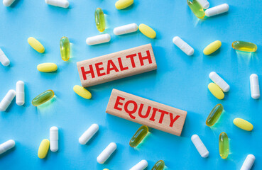 Health Equity symbol. Wooden blocks with words Health Equity. Beautiful blue background with pills. Medicine and Health Equity concept. Copy space.