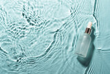 Fototapeta  - Serum bottle in the water on blue. Flat lay with copy space.