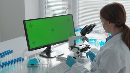 Aufkleber - Chroma key green screen. A laboratory where the scientist conducts research in the field of medicine and chemistry. Using a microscope, he studies biological structures, and using a computer, he