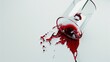   A glass containing red liquid sits atop a white table beside a tube releasing a drop