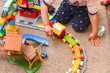 Child plays with toys, construction sets, and a railroad in the room on the floor.