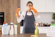 © Pixel-Shot - Displeased female janitor with air freshener covering nose in kitchen