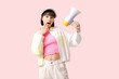 Surprised young woman with megaphone  on pink background