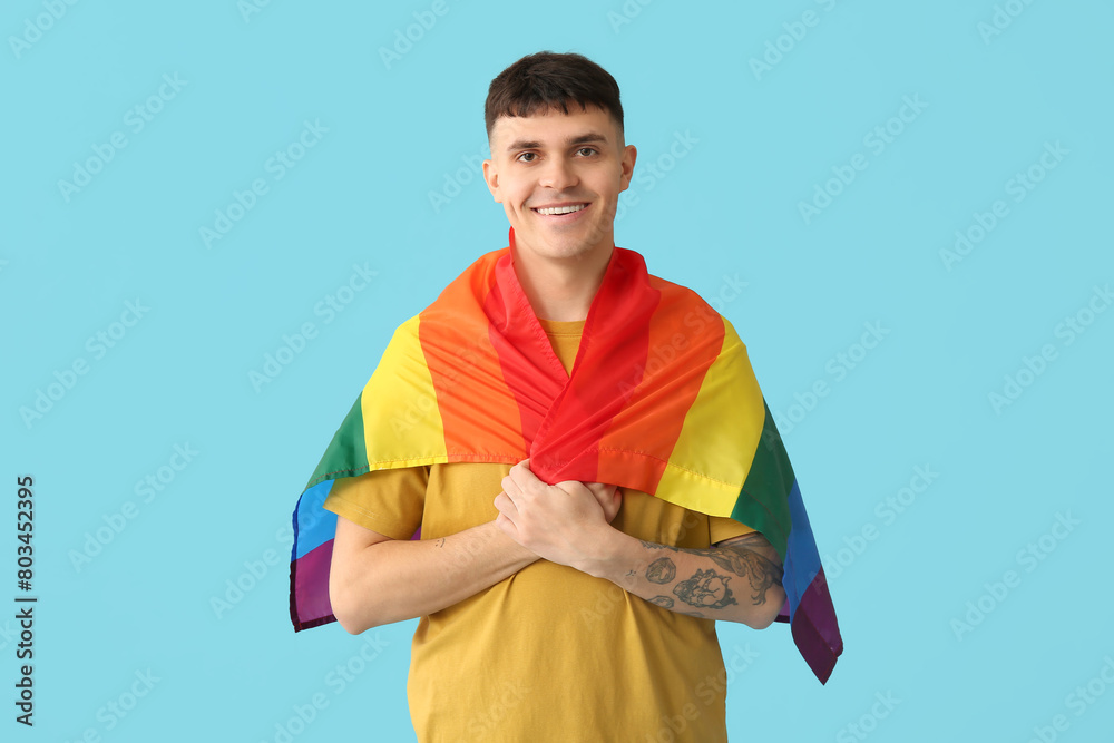 Handsome young happy man with LGBT flags on blue background
