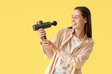 Canvas Print - Young woman with percussive massager on yellow background