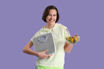 Beautiful young happy woman with scales and bowl of fresh salad on purple background. Weight loss concept