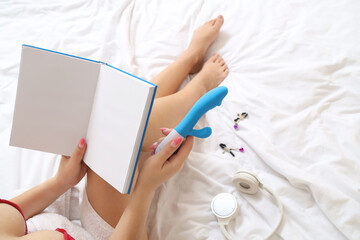 Wall Mural - Young woman with blank book, sex toys and headphones on bed