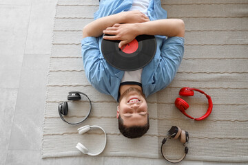 Sticker - Young bearded man with vinyl disk and headphones lying on floor, top view