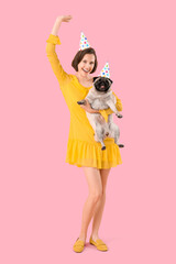 Canvas Print - Young woman and cute pug dog in party hats on pink background