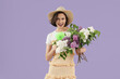 © Pixel-Shot - Young woman with green small electric fan and bouquet of lilac flowers on lilac background