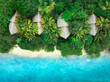 Aerial view of green palms, bungalows, white sandy beach, ocean with waves at sunset in summer. Top view of wooden houses, sea with azure water, trees. Luxury resort in Zanzibar. Tropical background