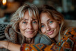 Happy blonde elderly mom and young daughter woman at home, looking  toothy smiles, laughing, hugging, enjoying warm family relationship