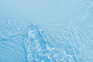 Blue water with ripples on the surface. Defocus blurred transparent blue colored clear calm water surface texture with splashes and bubbles. Water waves with shining pattern texture background.