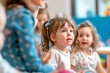 © MVProductions - Group of small nursery school children sitting and listening to teacher on floor indoors in classroom