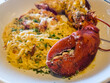 Giant lobster claw and split lobster tail on a plate of pasta