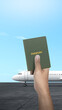Human hand holding a passport for traveling on the runway
