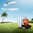 Portrait of a woman in hijab with a suitcase using a mobile phone while traveling with an airplane flying
